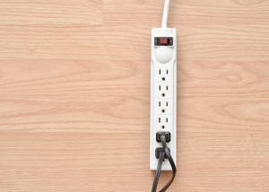Closeup of a power bar with cords in it on a wood floor.