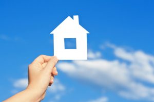 cardboard-house-in-the-hand-against-the-blue-sky