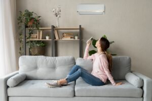 woman-on-couch-using-remote-to-turn-on-ductless-air-handler