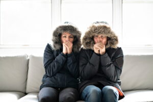 man-and-woman-sitting-on-couch-with-coats-and-hoods-on