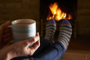 woman-holding-coffee-with-feet-up-in-front-of-fireplace