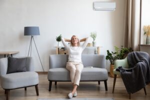 middle-aged-woman-sits-on-couch-with-hands-behind-head-relaxing